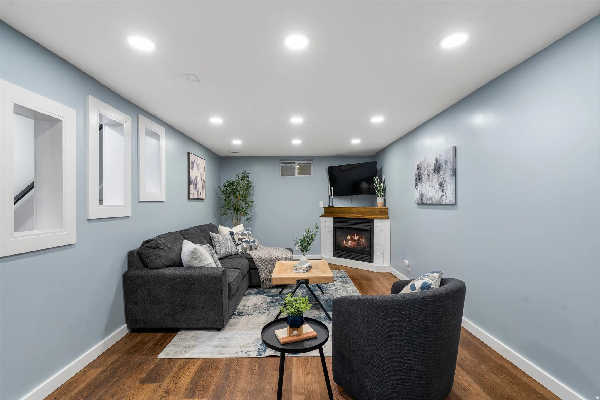 Recessed lighting illuminates wood-finish flooring and fireplace