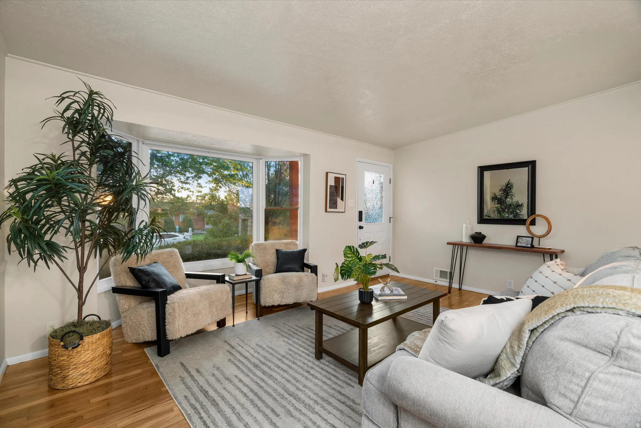 Hardwood flooring, bay window, white paneled door with frosted glass, and white trim