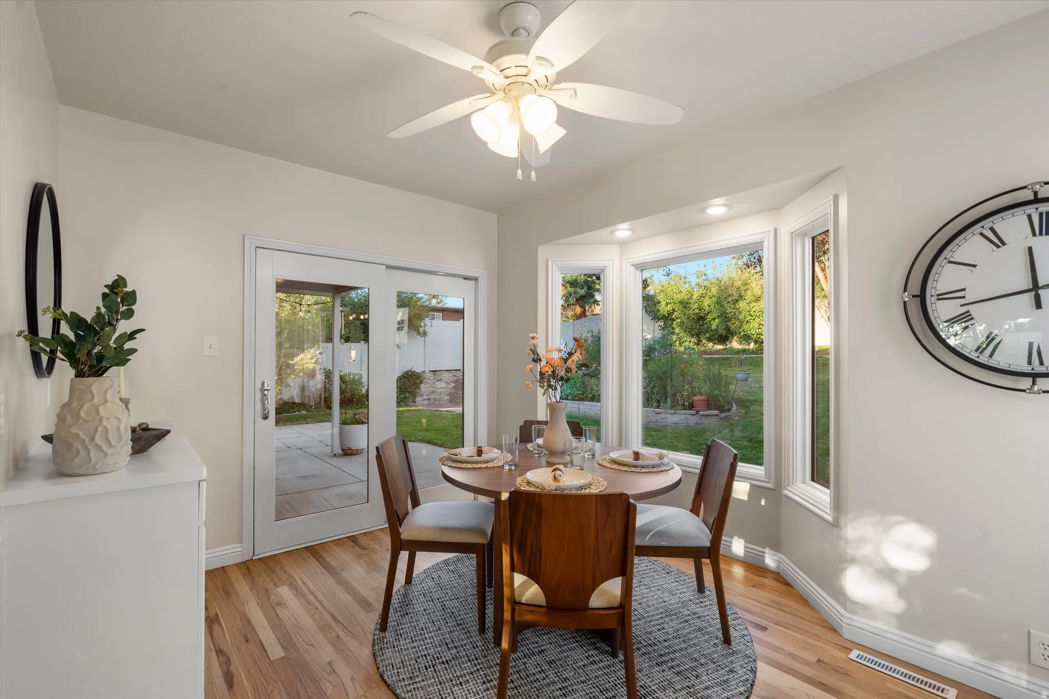 Bay window  dining nook with built-n cabinetry, a ceiling fan and backyard access