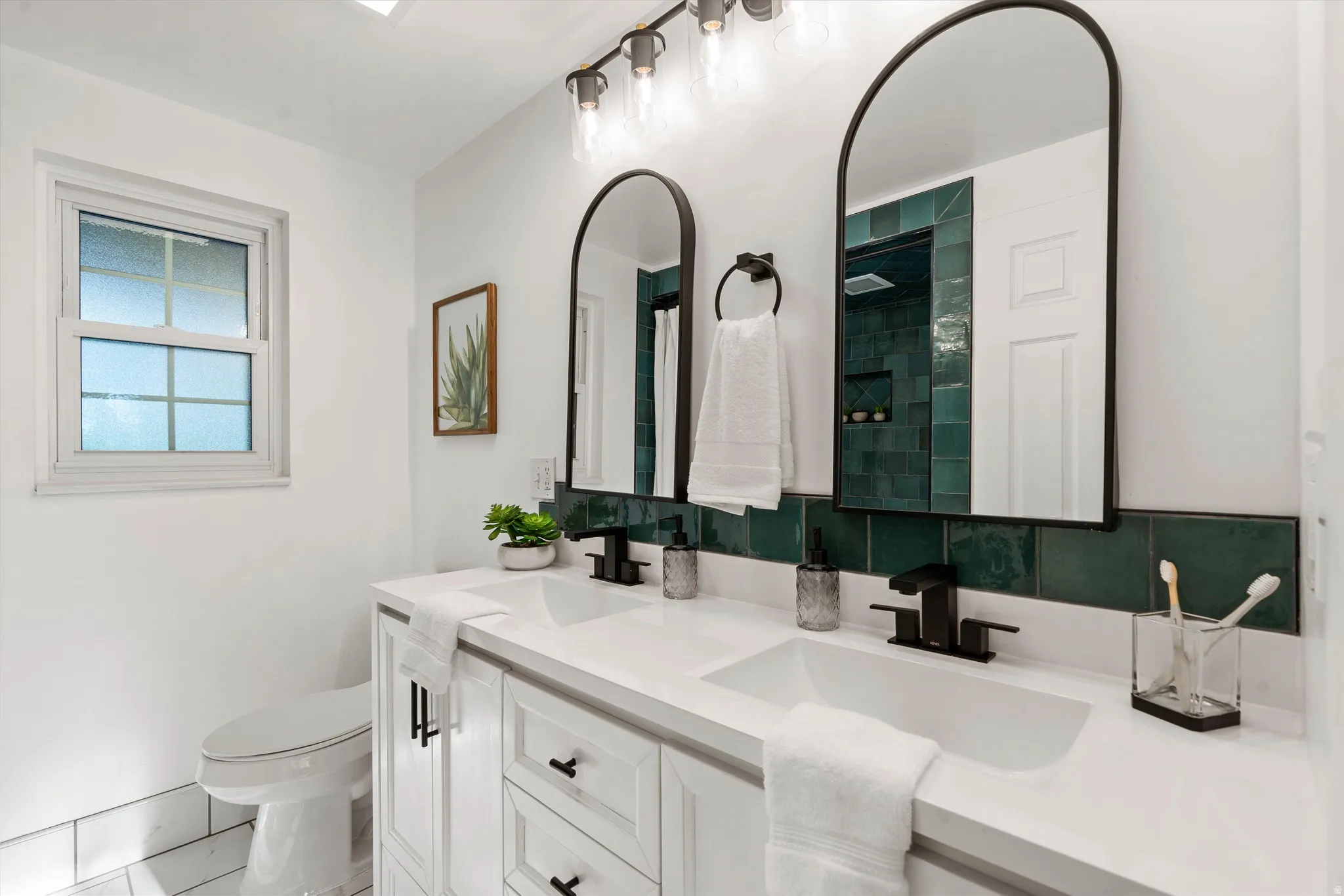 Dual vanity with white cabinetry, black hardware, white countertops, and integrated rectangular sinks
