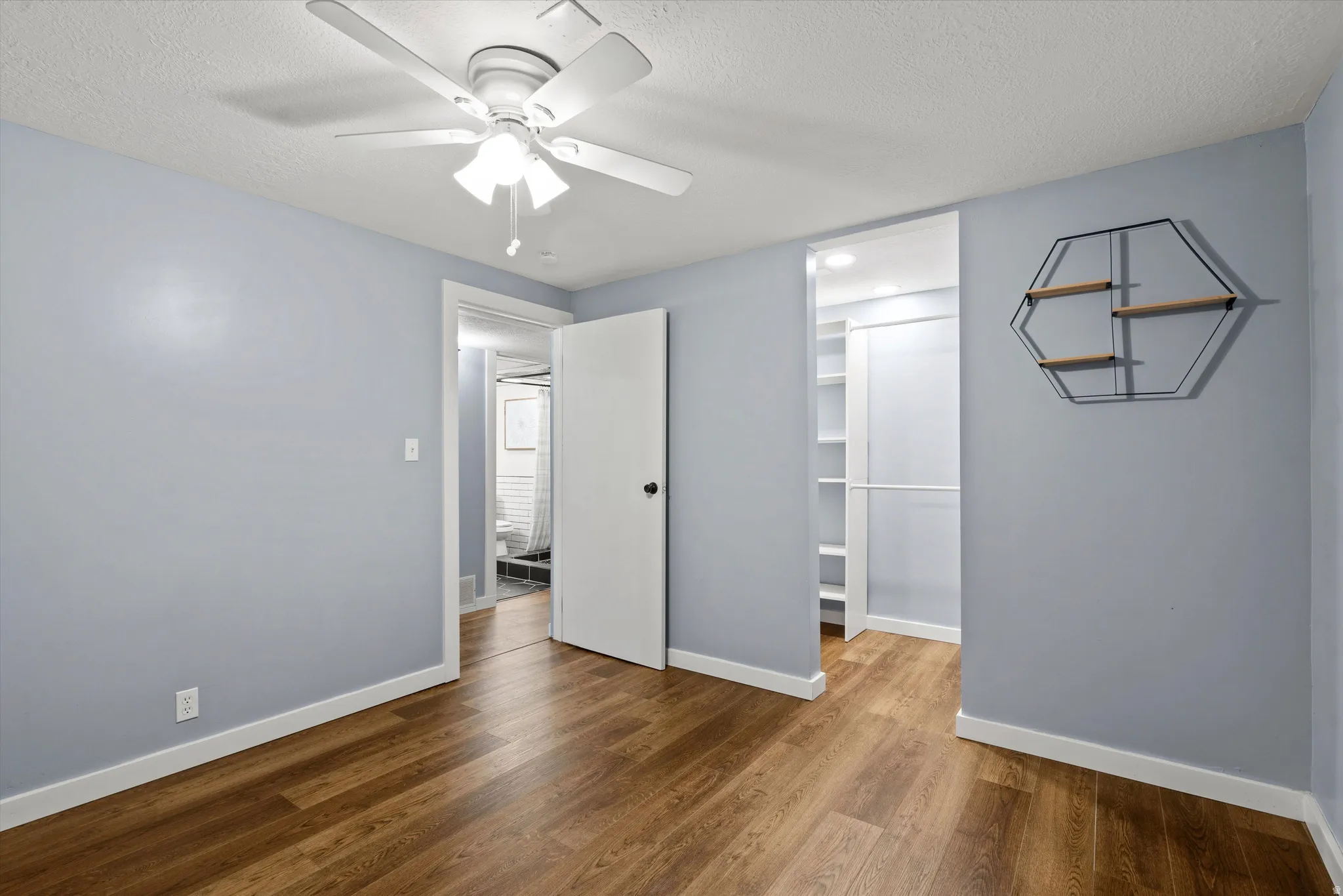 Bedroom #4 Wood-finish flooring, ceiling fan with integrated lighting, and a built-in closet system