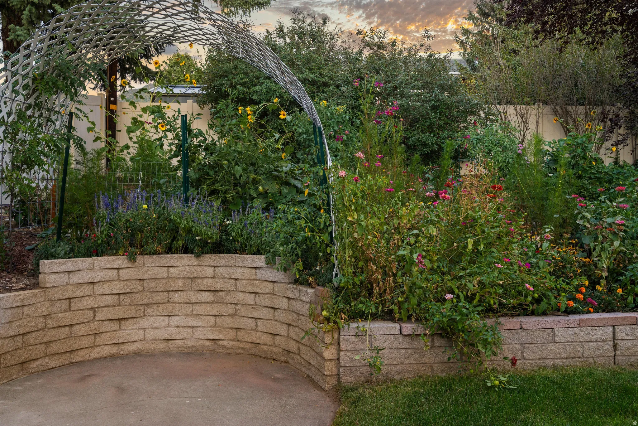 Landscaped garden featuring a decorative arch trellis, mature plantings, and a stone retaining wall