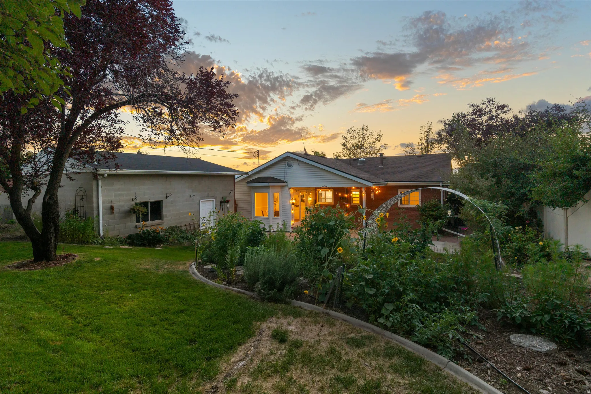 Expansive backyard featuring a manicured lawn, established garden beds, and mature trees