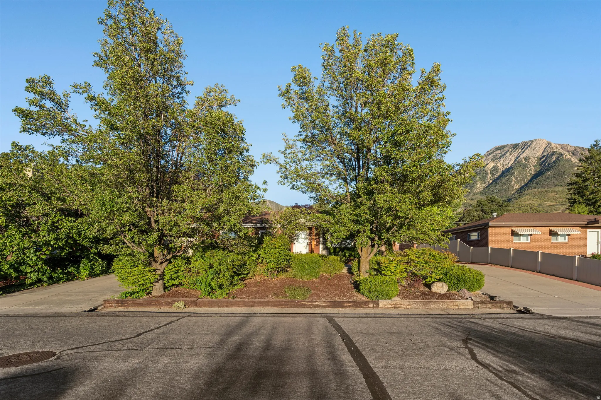 Mature trees and shrubs provide privacy, complemented by a prominent mountain backdrop
