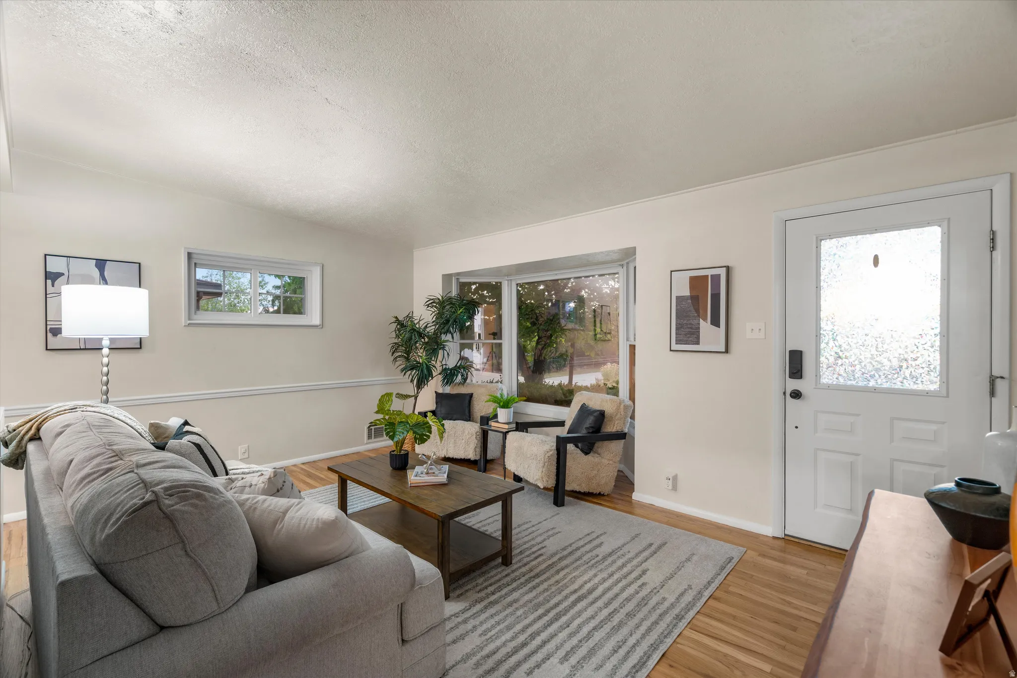 Natural hardwood, white walls, and a white entry door with frosted glass
