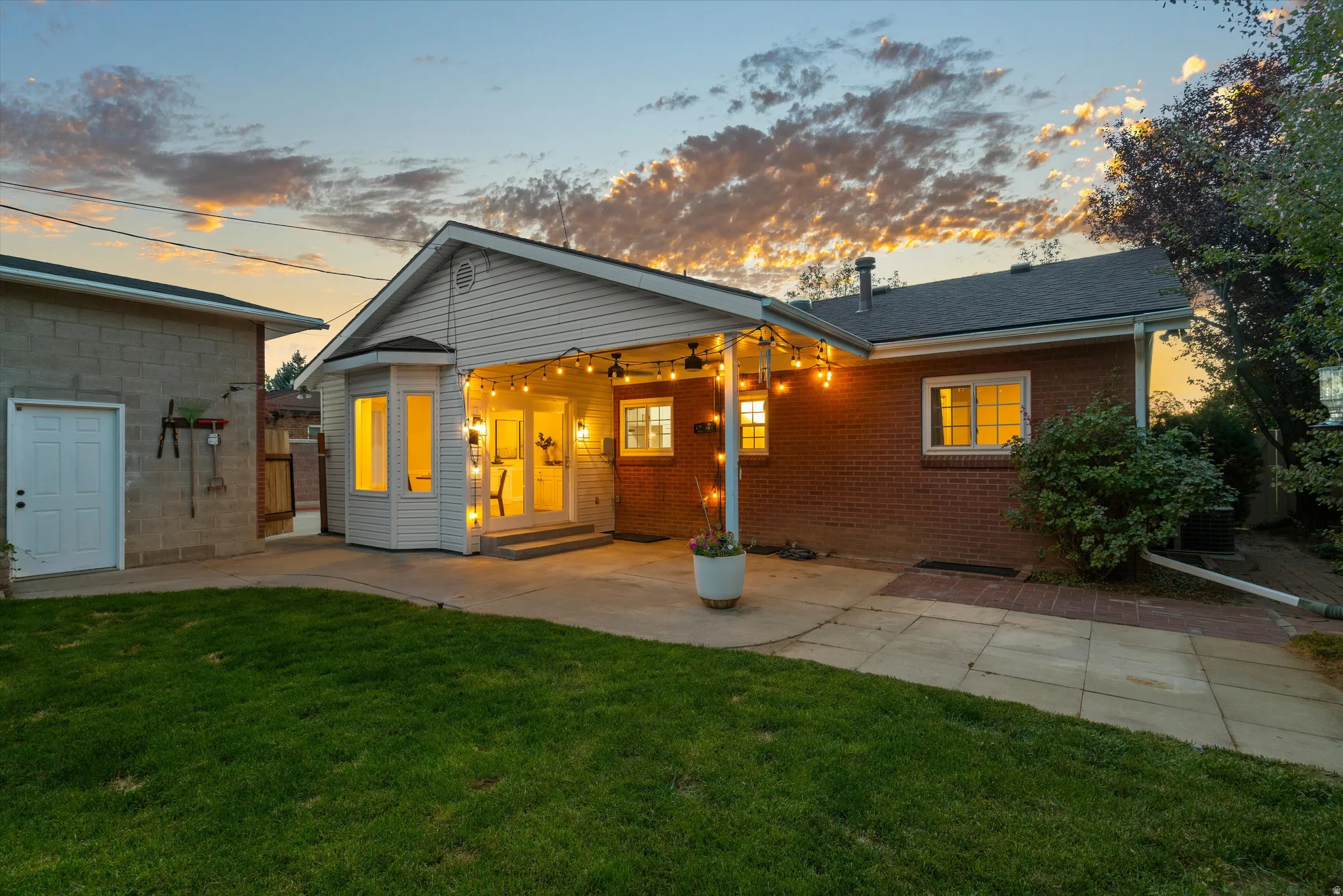 Expansive backyard featuring a manicured lawn, brick exterior, and a dedicated patio area
