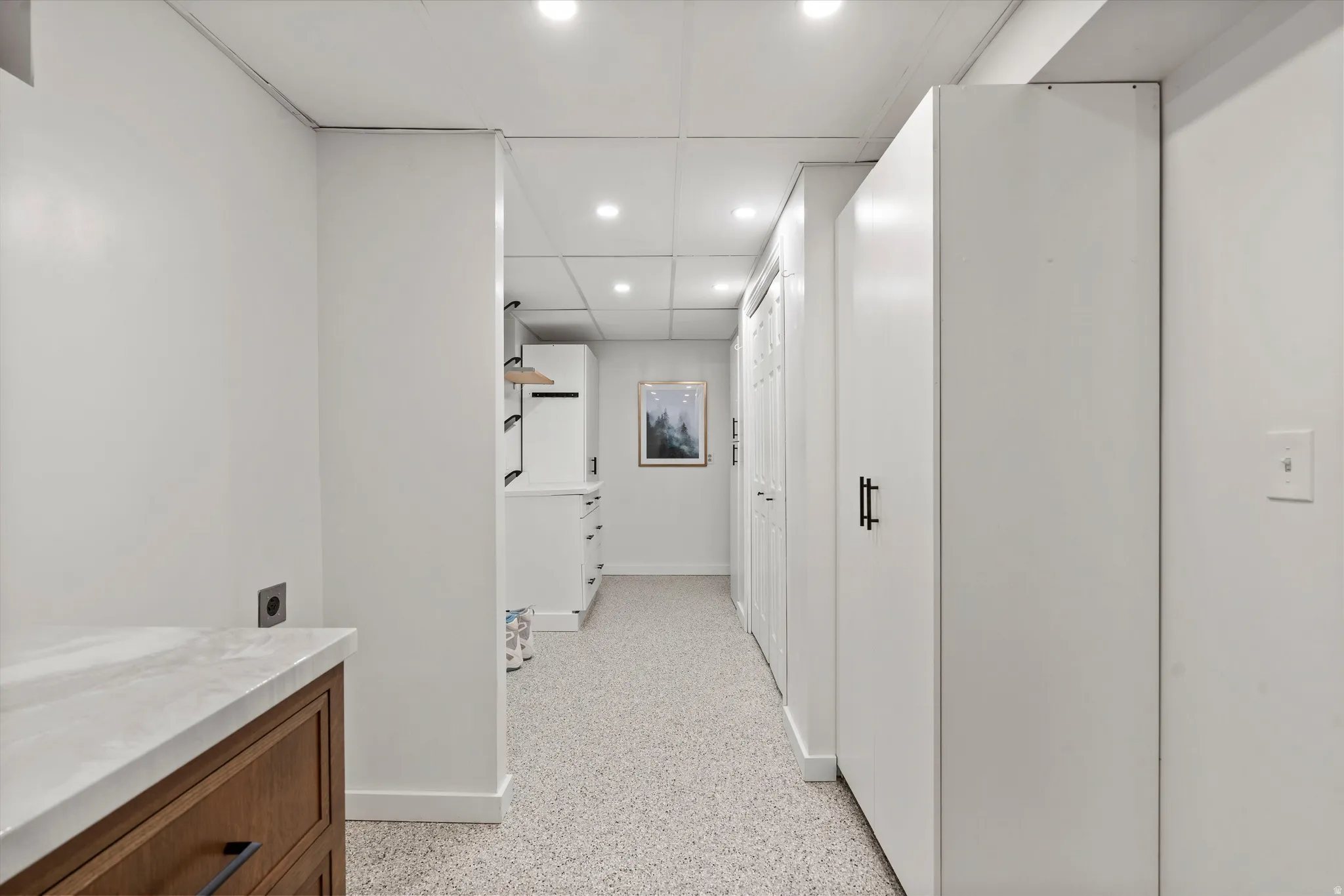 Area off of laundry room. Built-in cabinetry, wood-finish drawers, stone-finish countertop, recessed lighting, and epoxy flooring.