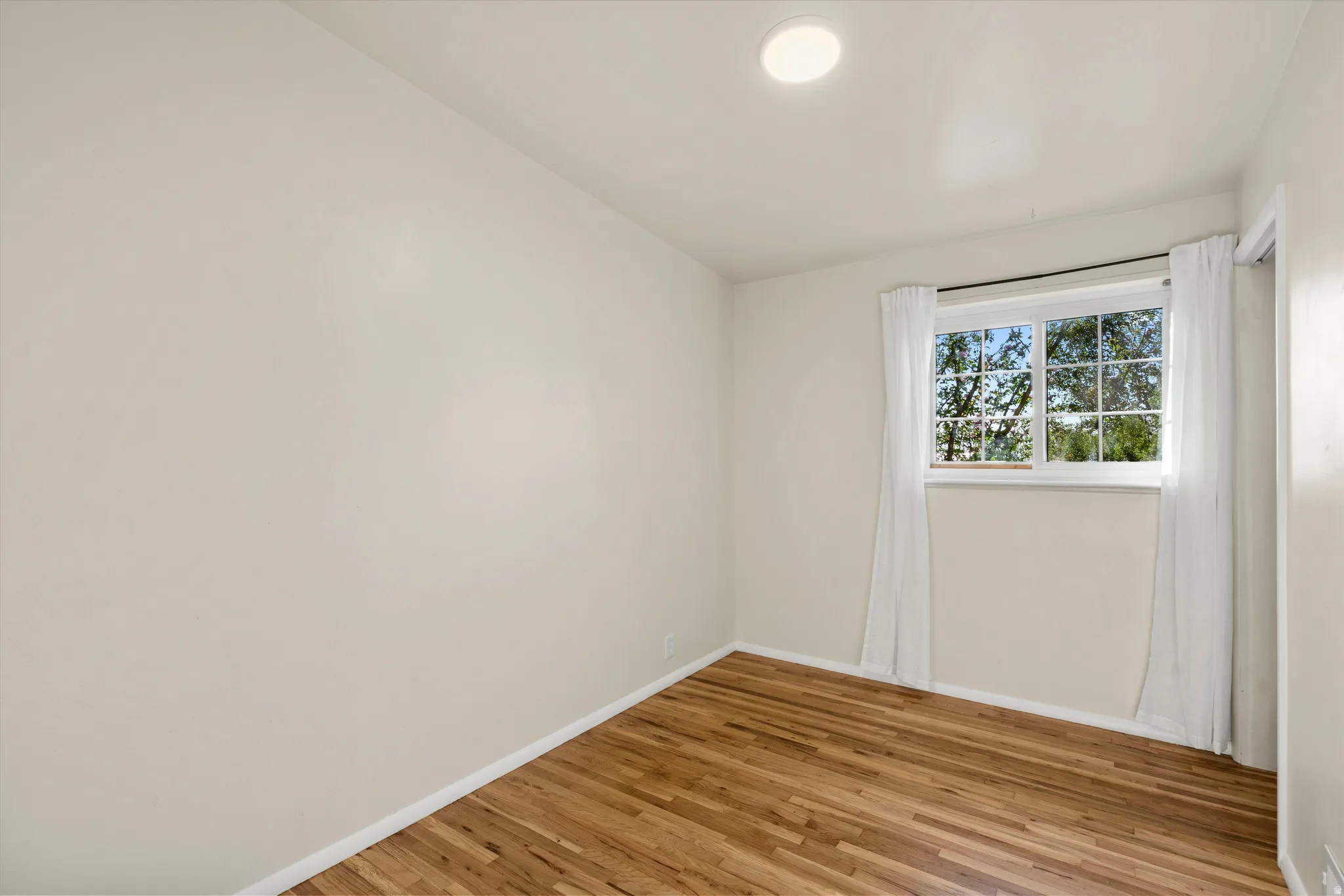 Bedroom #3 Recessed ceiling light, hardwood flooring, white trim, and a window with grid detailing