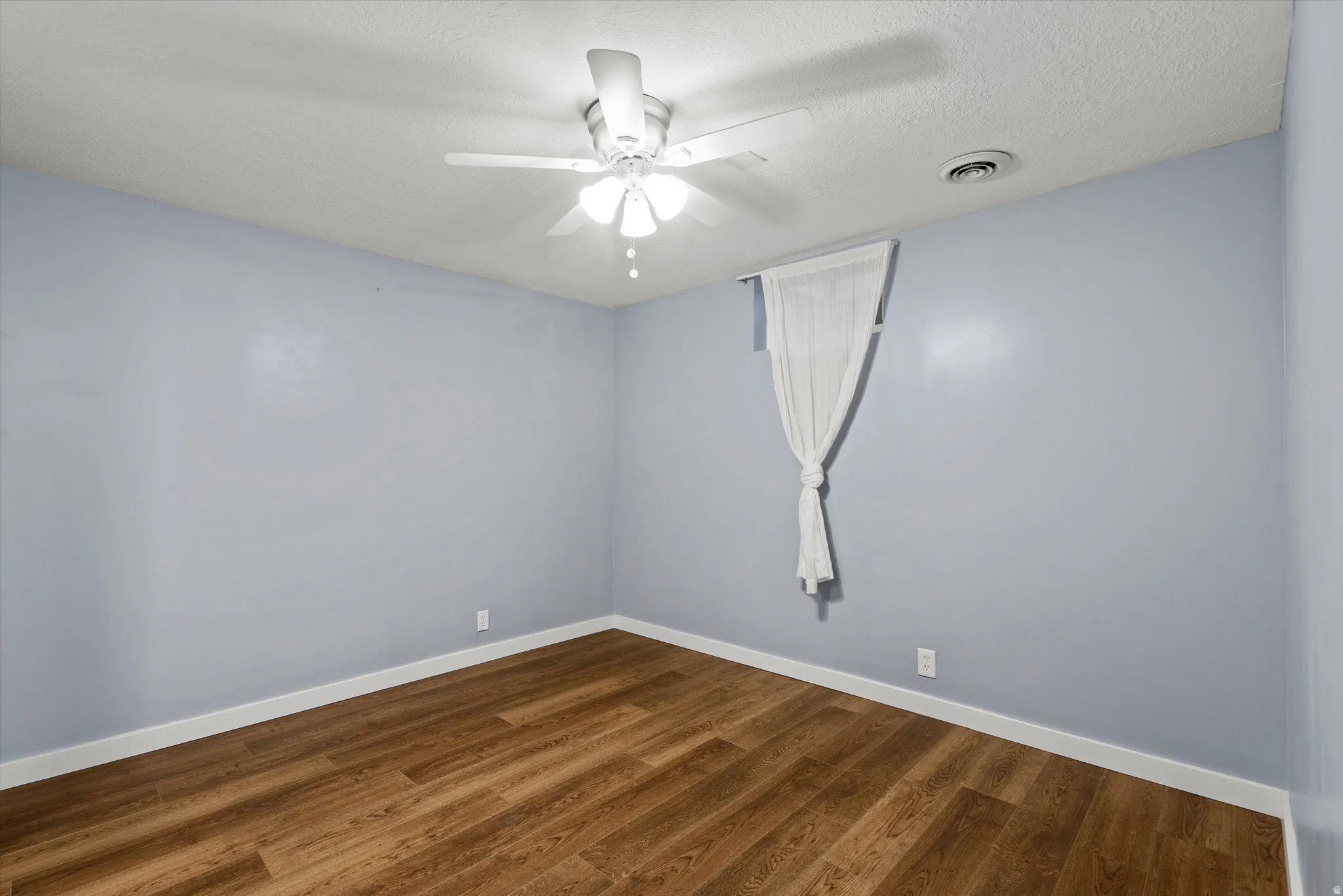 Bedroom #4 Wood-finish flooring with white trim, light blue walls, and a ceiling fan with integrated lighting