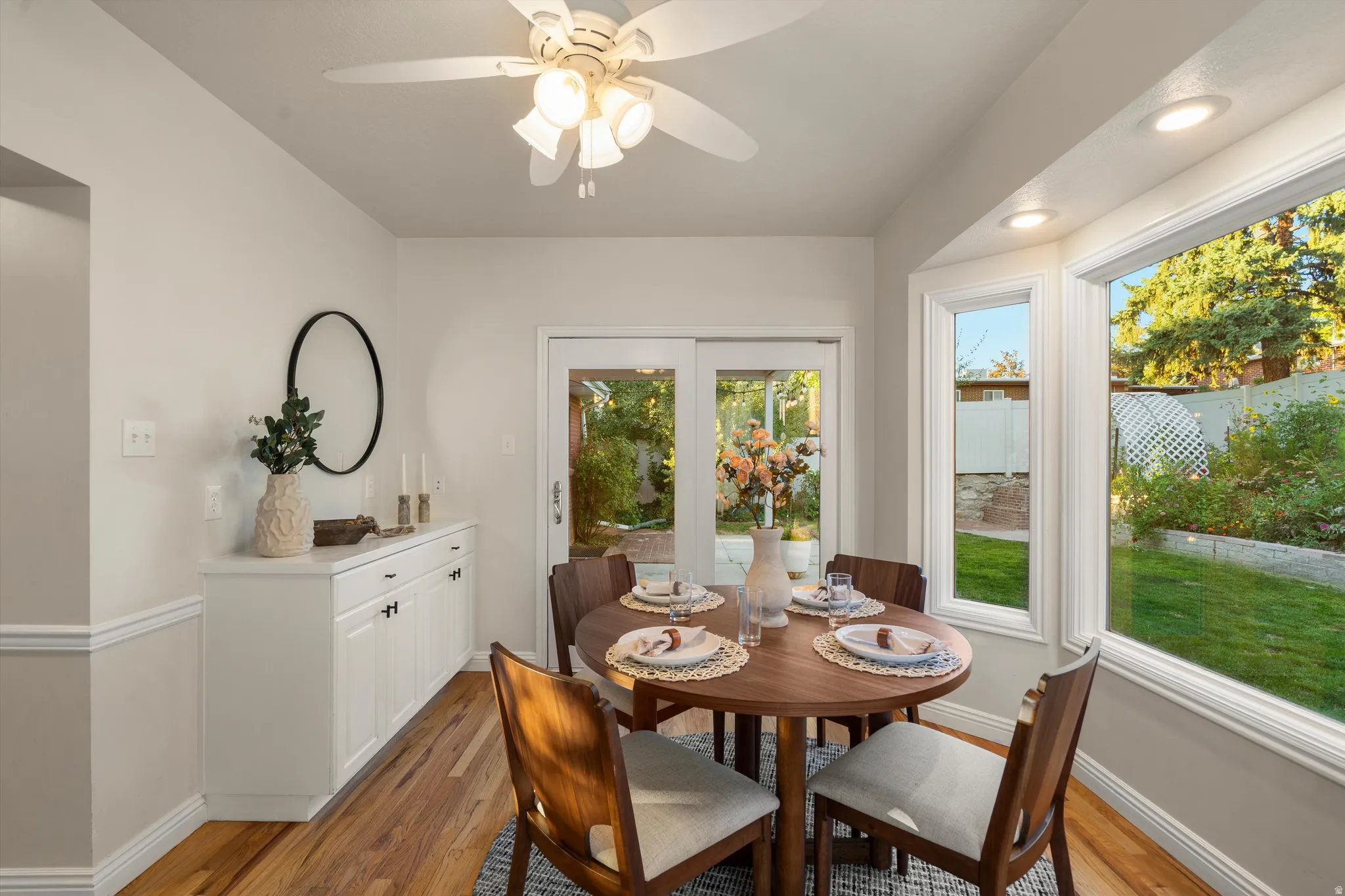 Bay window  dining nook with built-n cabinetry, a ceiling fan and backyard access