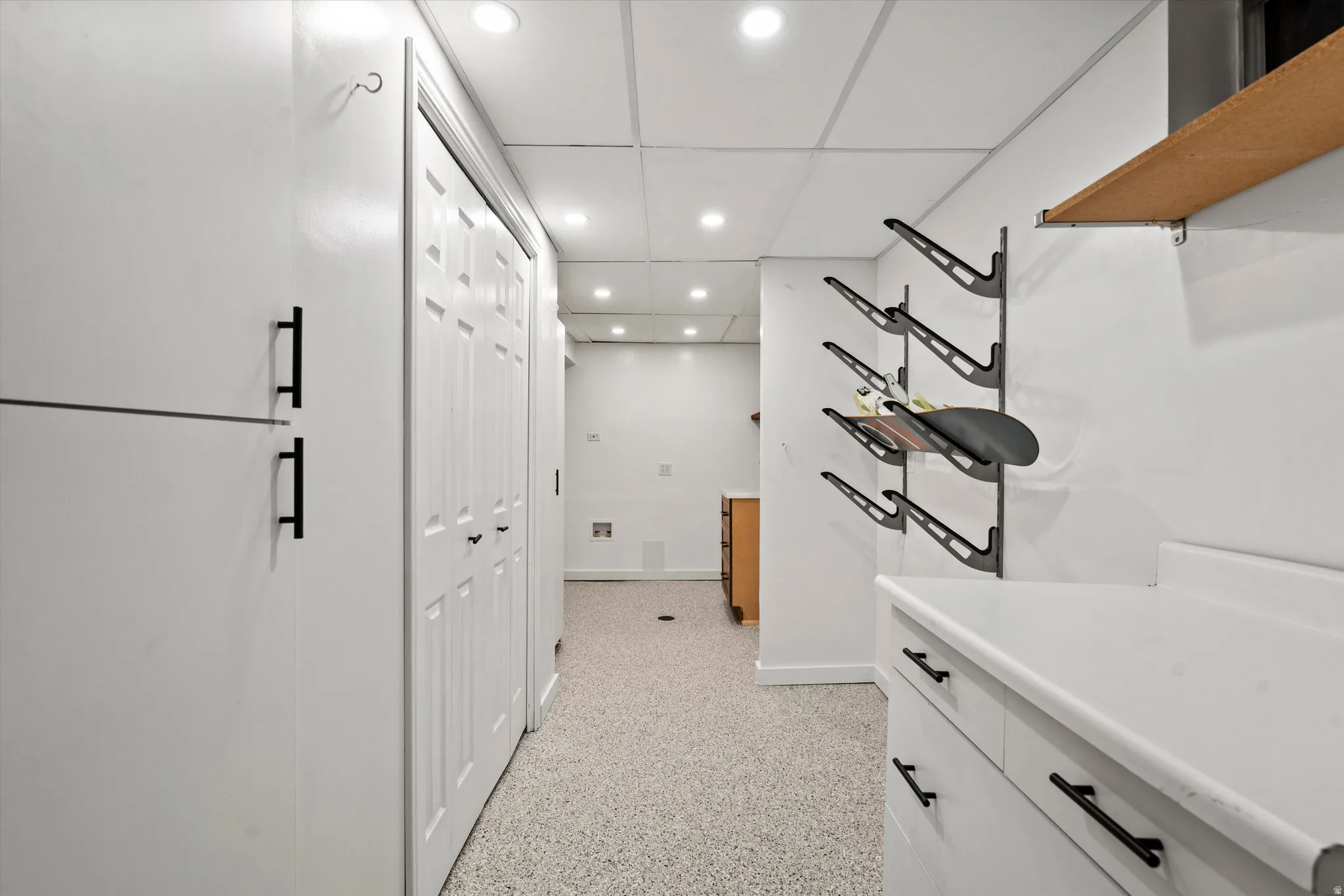 Recessed lighting illuminates the space, featuring white cabinetry with black hardware, a light-toned countertop.