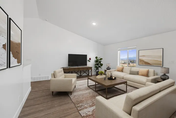 Spacious living area featuring wood-finish flooring, vaulted ceilings, and a large window