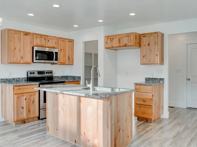 Kitchen featuring wood cabinetry, granite countertops, stainless steel appliances, and wood-finish flooring
