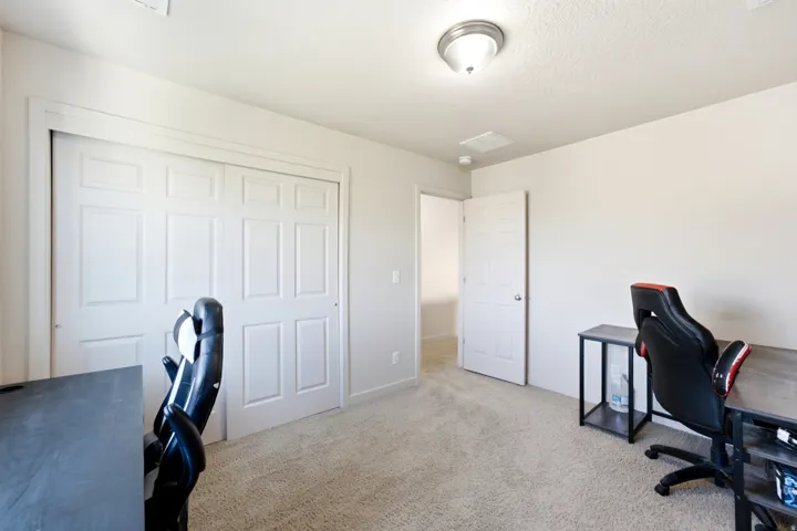 Carpeted flooring, white paneled bifold closet doors, white paneled interior door, and a ceiling-mounted light fixture