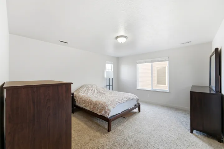White walls with carpet flooring, complemented by a large window and a flush-mount ceiling light fixture