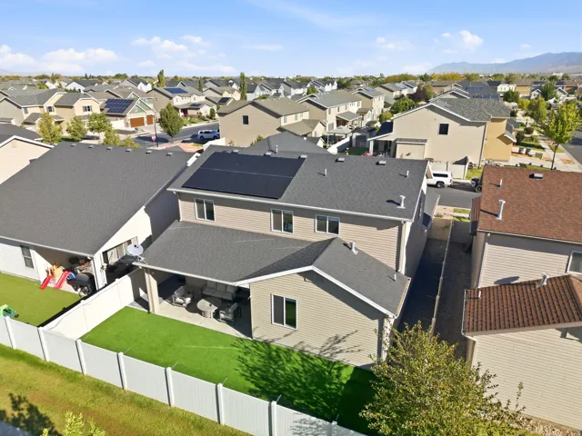 Rear exterior with solar panels, covered patio, artificial turf, and white privacy fencing