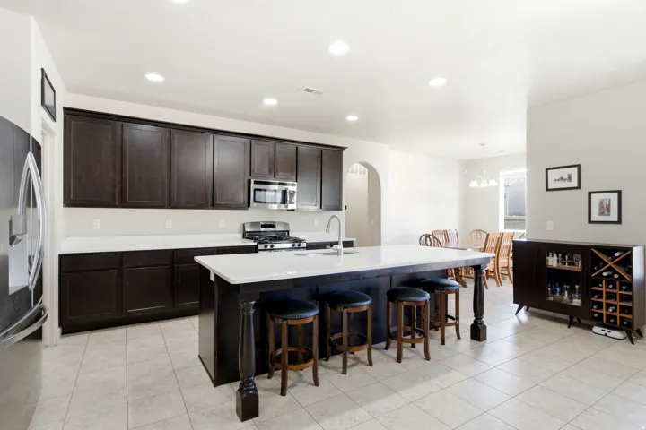 Kitchen featuring dark wood-finish cabinetry, white countertops, stainless steel appliances, and a central island with integrated seating