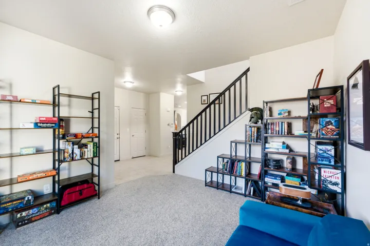 Carpeted flooring, white interior walls, and a staircase with dark balusters