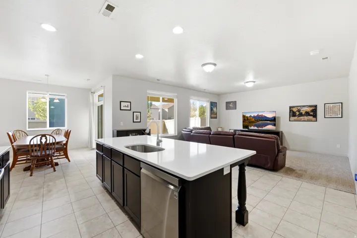 Kitchen island with white countertop, dark cabinetry, and integrated stainless steel sink