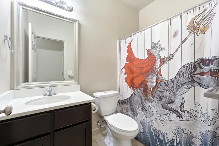 Vanity with a white countertop and dark wood cabinetry, framed mirror, and a white toilet