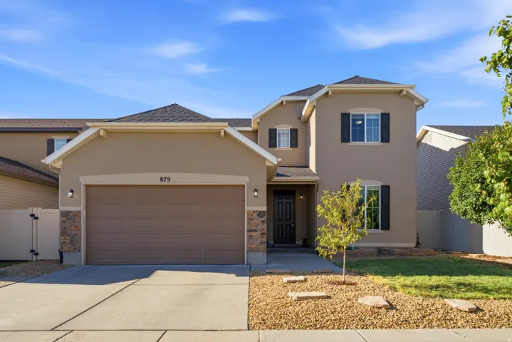 Stucco exterior with stone accents, attached two-car garage, dark-toned front door, dark window shutters, and a concrete driveway