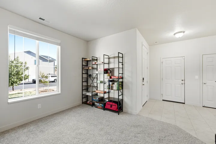 Bright interior with a large window, neutral carpeting, and a tile entry