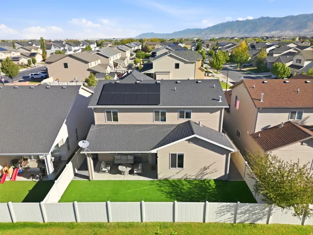 Rear exterior with a covered patio, artificial turf, and white privacy fencing