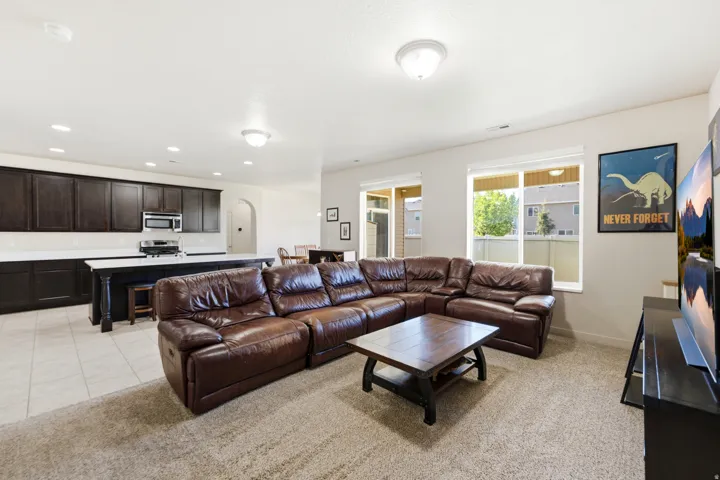 Open-concept living space featuring a kitchen with dark wood-finish cabinetry, white countertops, and stainless steel appliances