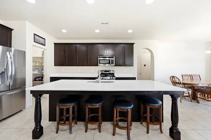 Kitchen featuring dark wood cabinetry, stainless steel appliances, a center island with countertop seating, and recessed lighting