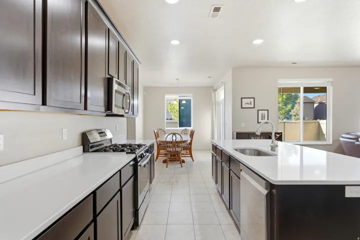 Kitchen featuring dark wood cabinetry, white countertops, stainless steel appliances, and recessed lighting