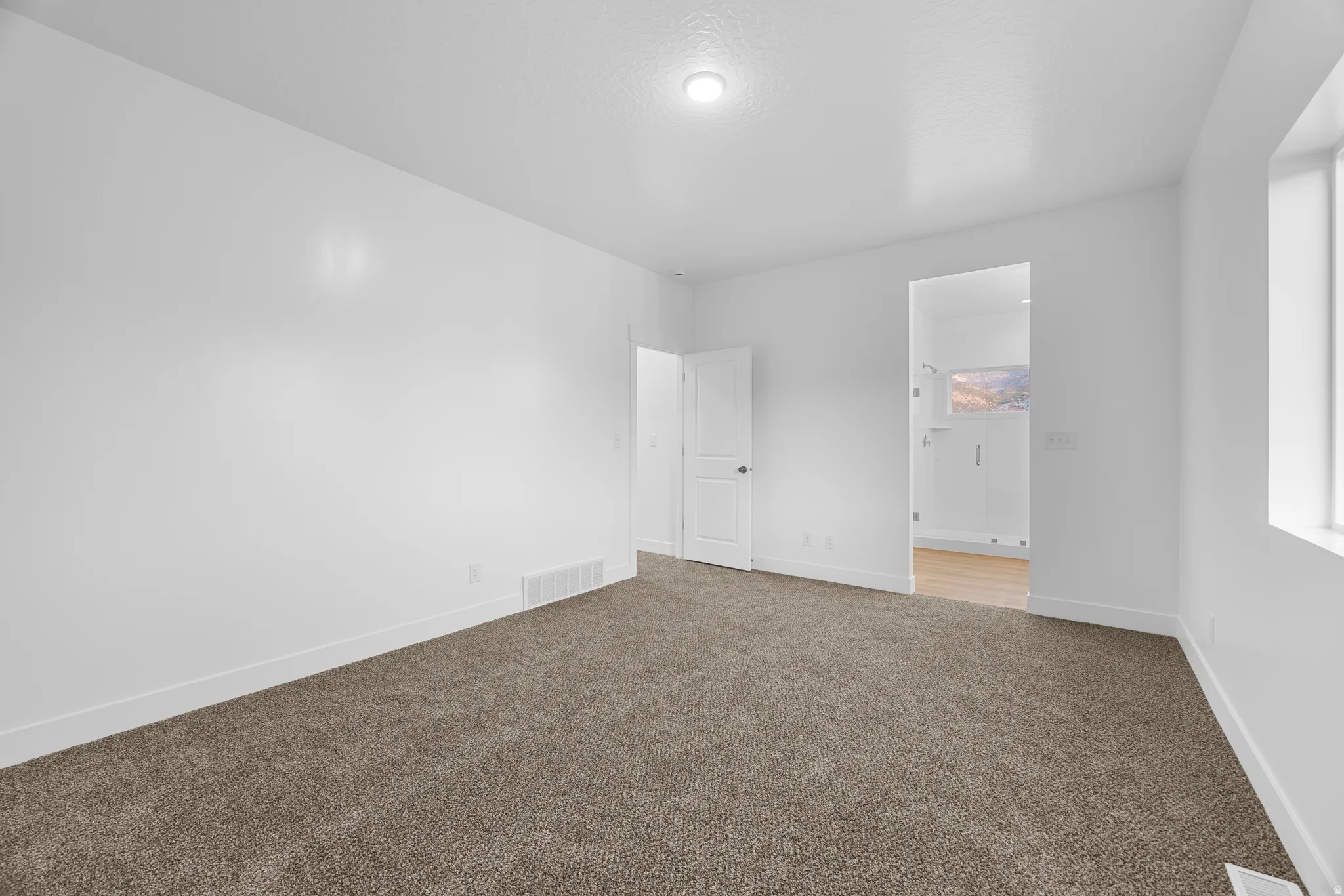 Plush carpet flooring, neutral paint palette, recessed lighting, and a window with natural light