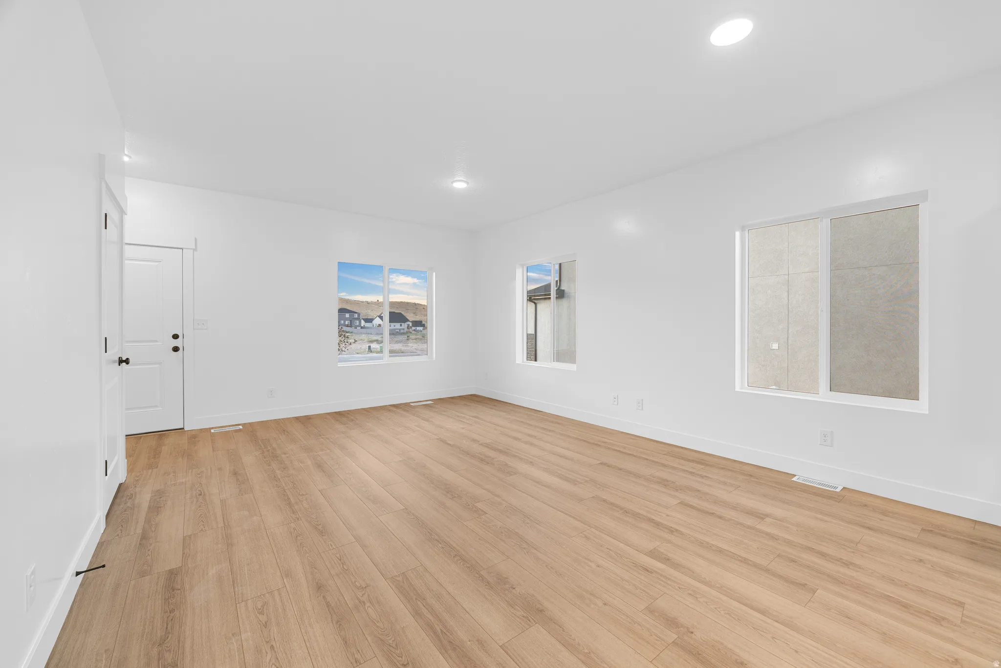 Bright interior featuring recessed ceiling lights, white walls, and light wood-finish flooring