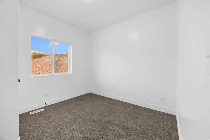 Window with exterior scenery, neutral tone carpeting, and crisp white walls
