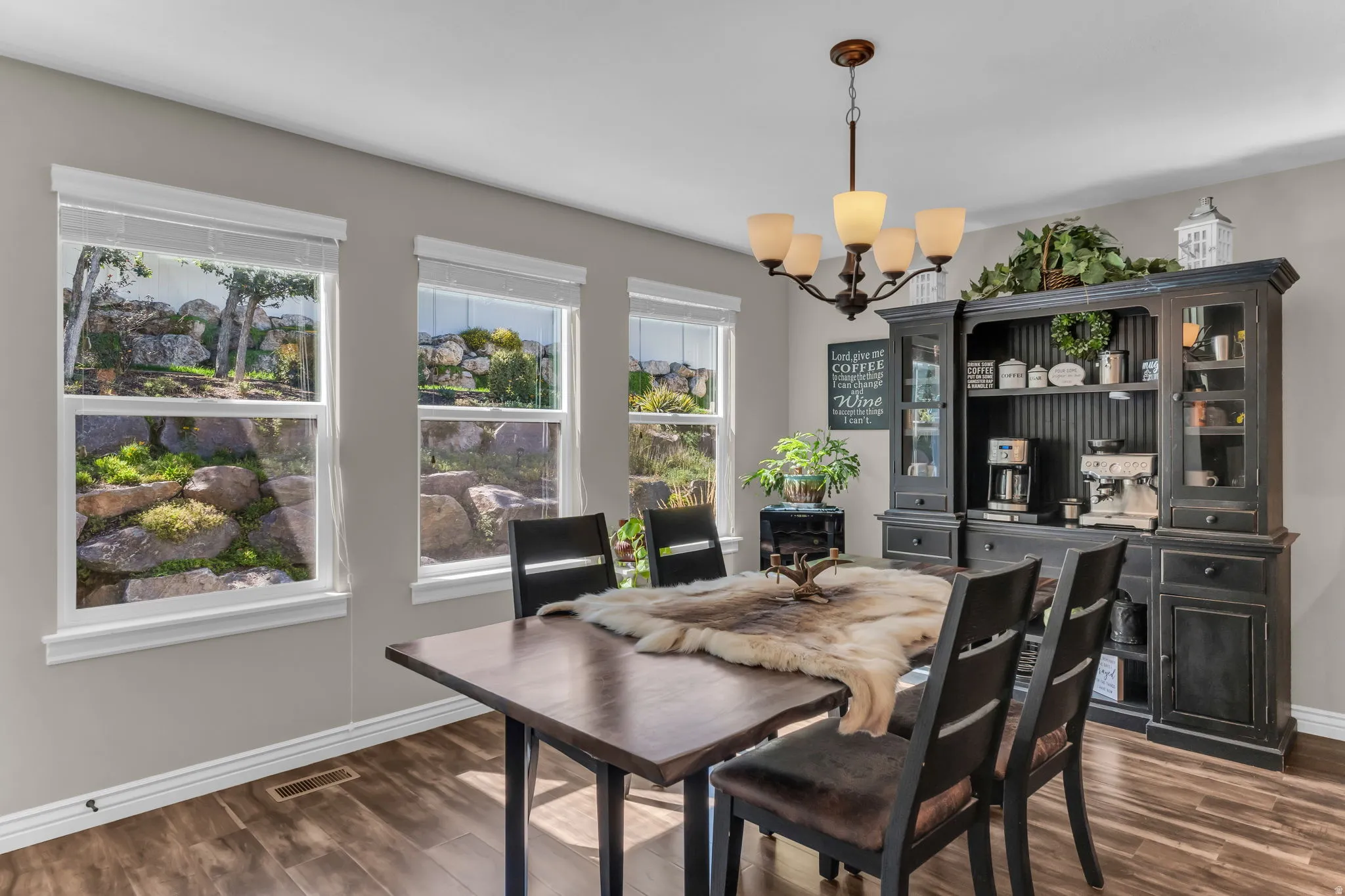 Wood-finish flooring, multiple windows, built-in cabinetry, and a chandelier with glass shades