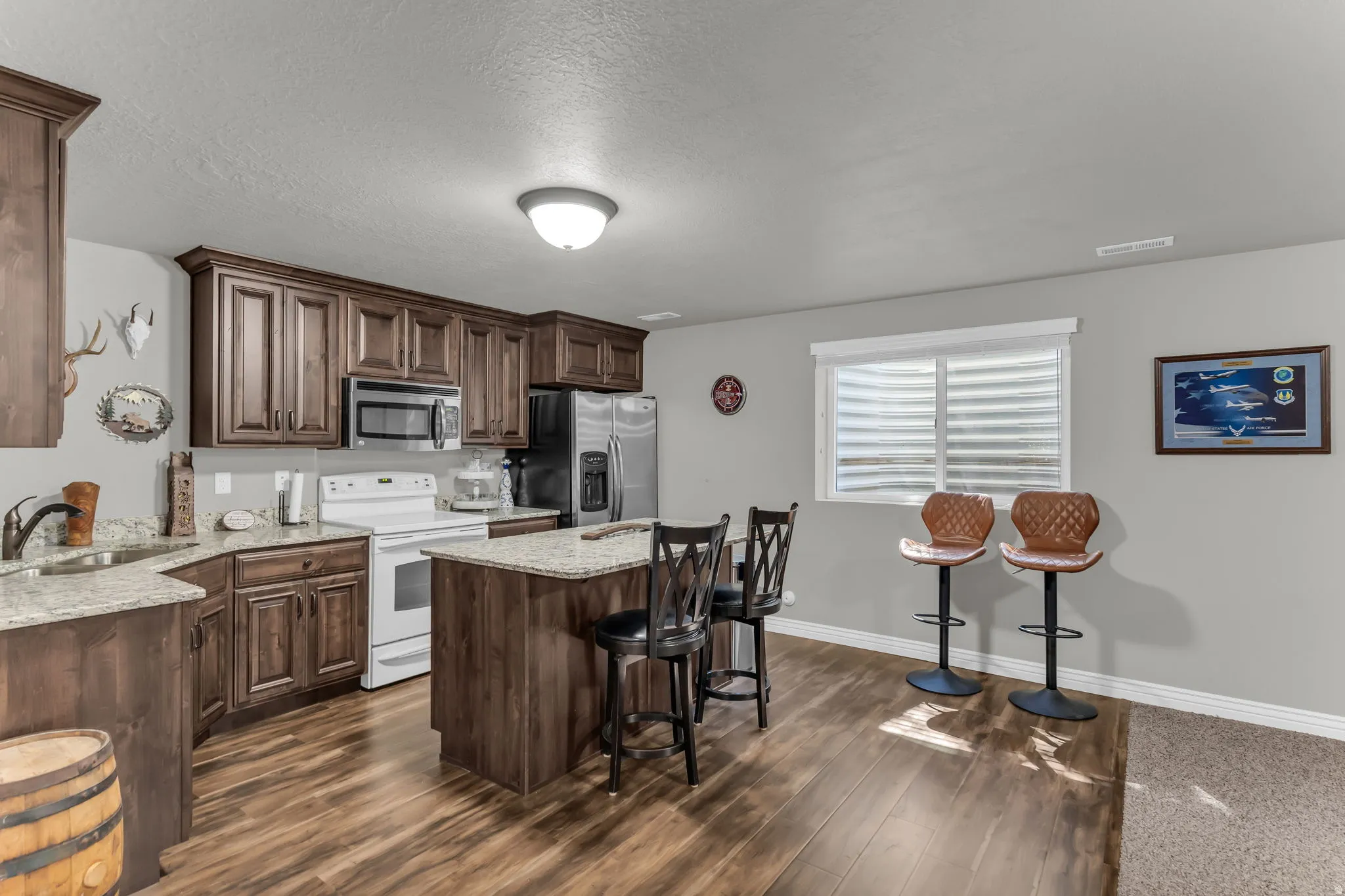 Kitchen featuring wood-finish flooring, dark wood cabinetry, light-toned countertops, and a central island with bar seating