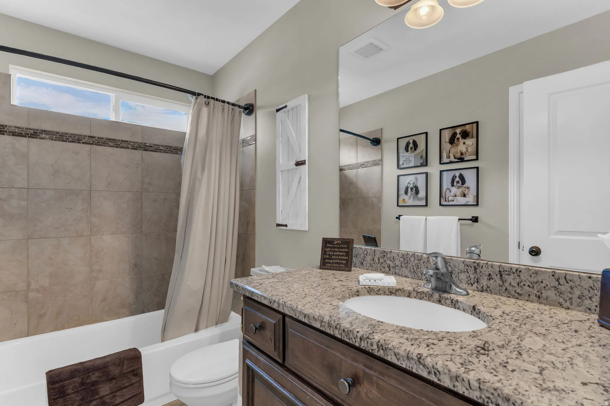 Spacious vanity with a light granite-finish countertop, wood-finish cabinetry, and a large mirror