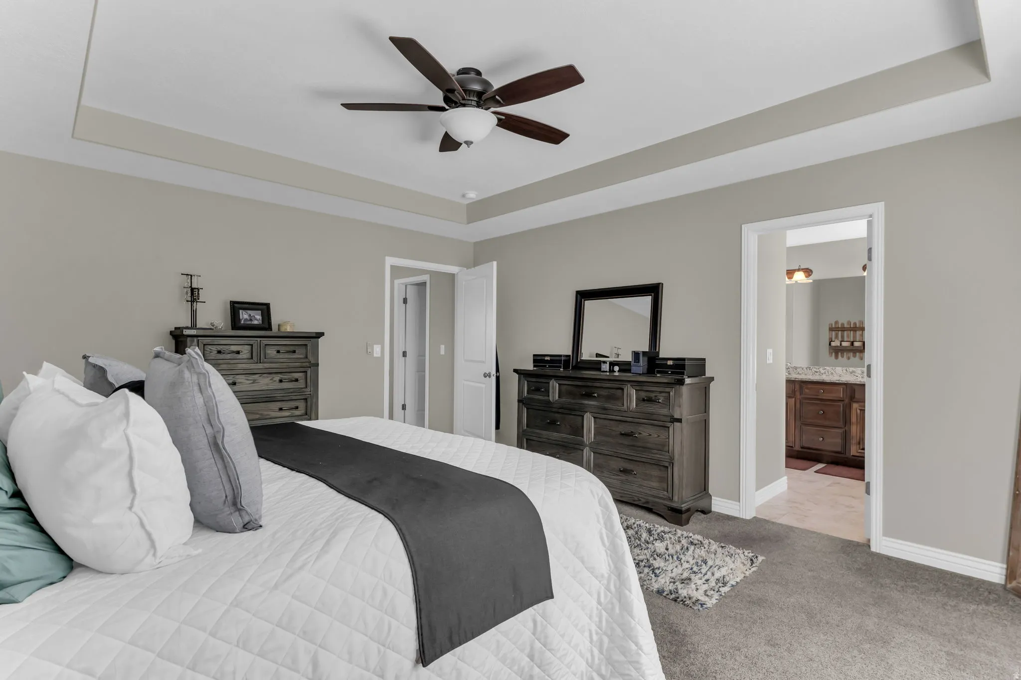 Tray ceiling with ceiling fan, neutral wall tones, and carpeted flooring