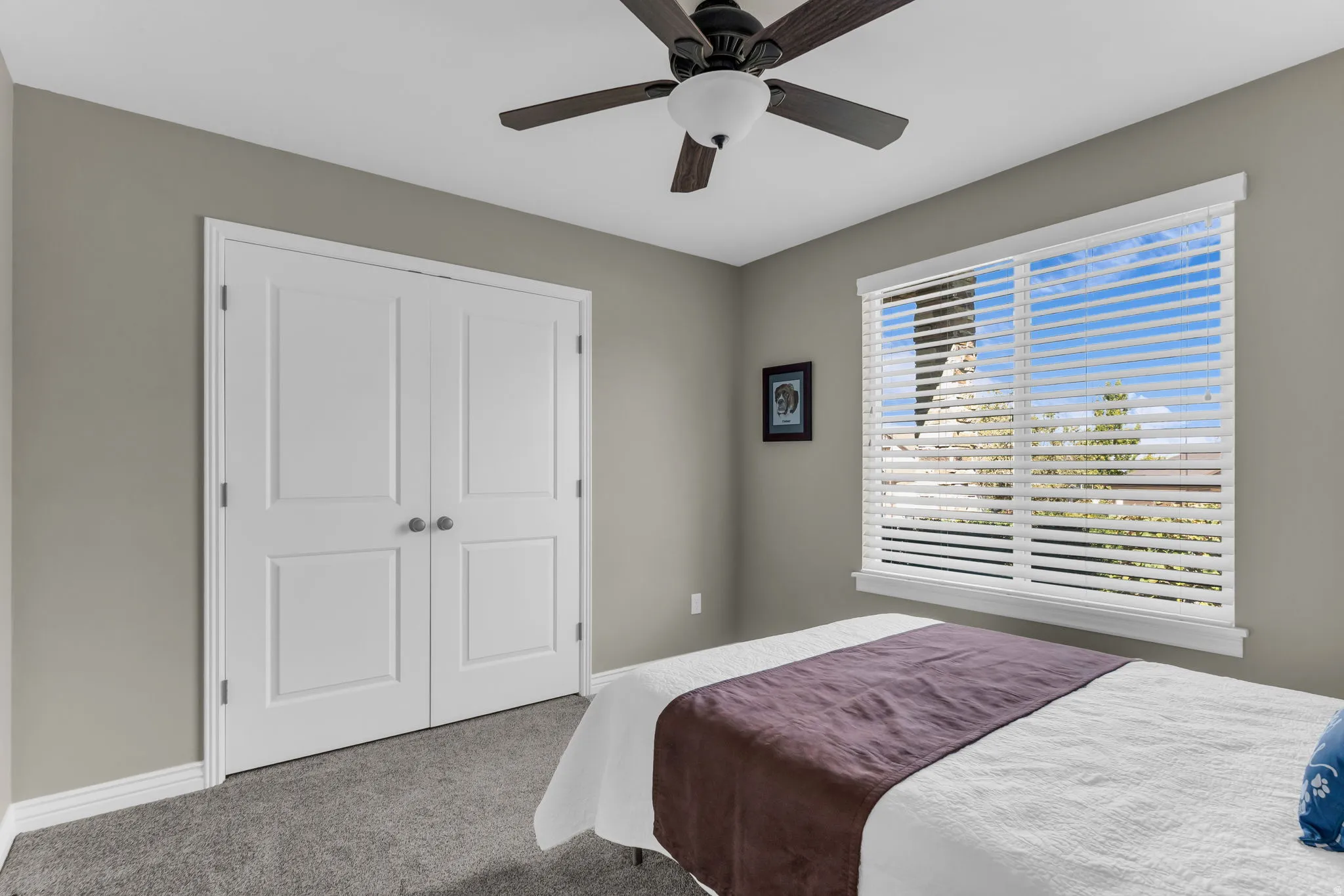 Recessed window with horizontal blinds, built-in ceiling fan with integrated lighting, paneled double doors, and soft gray carpeting