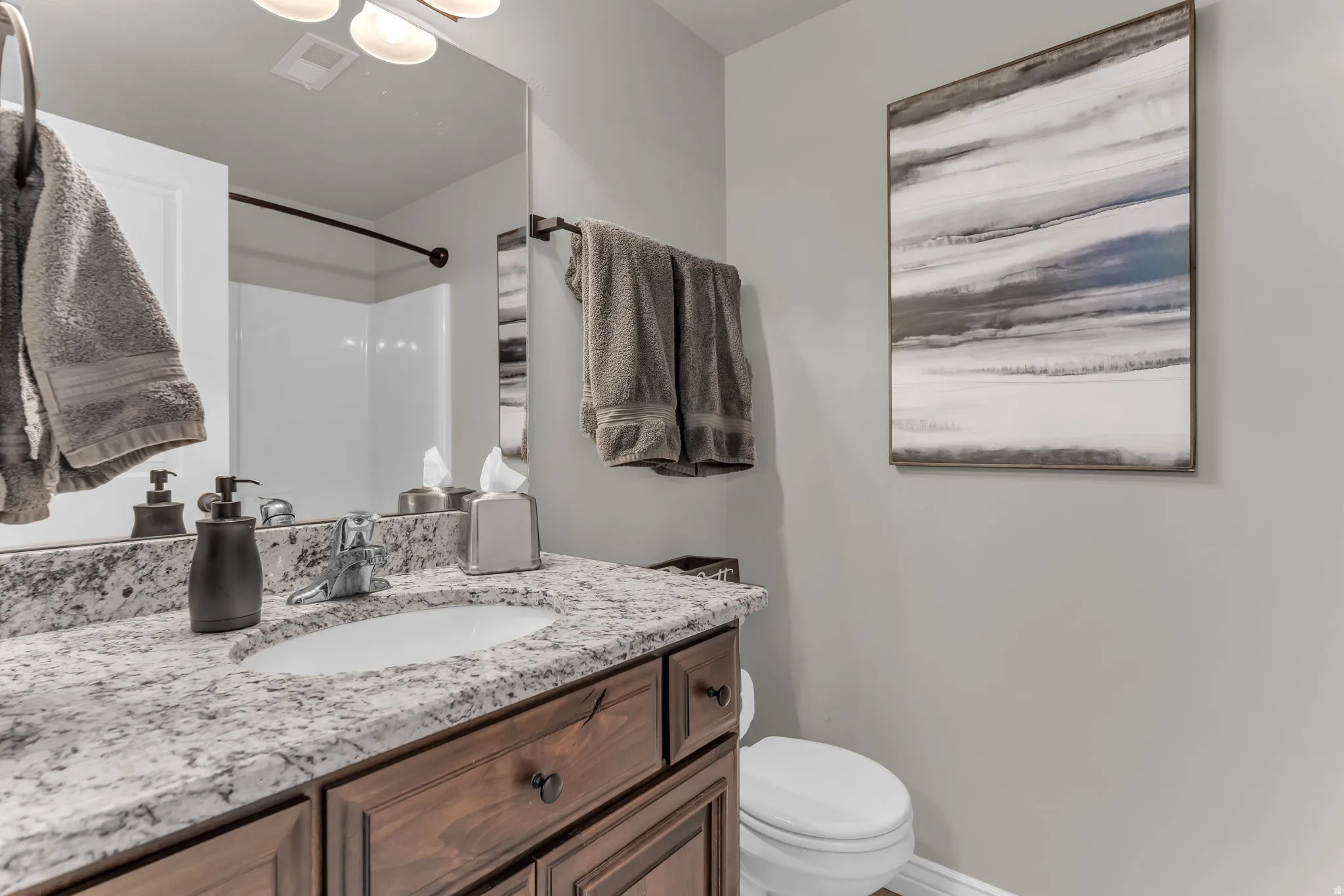 Vanity with a granite countertop, undermount sink, and wood-finish cabinetry