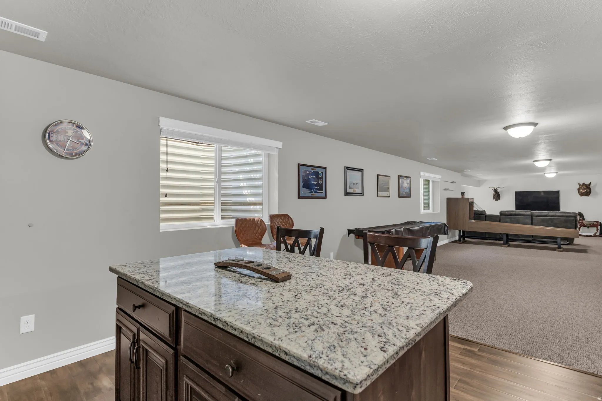 Kitchen island with granite countertop, dark wood-finish cabinetry, and wood-finish flooring