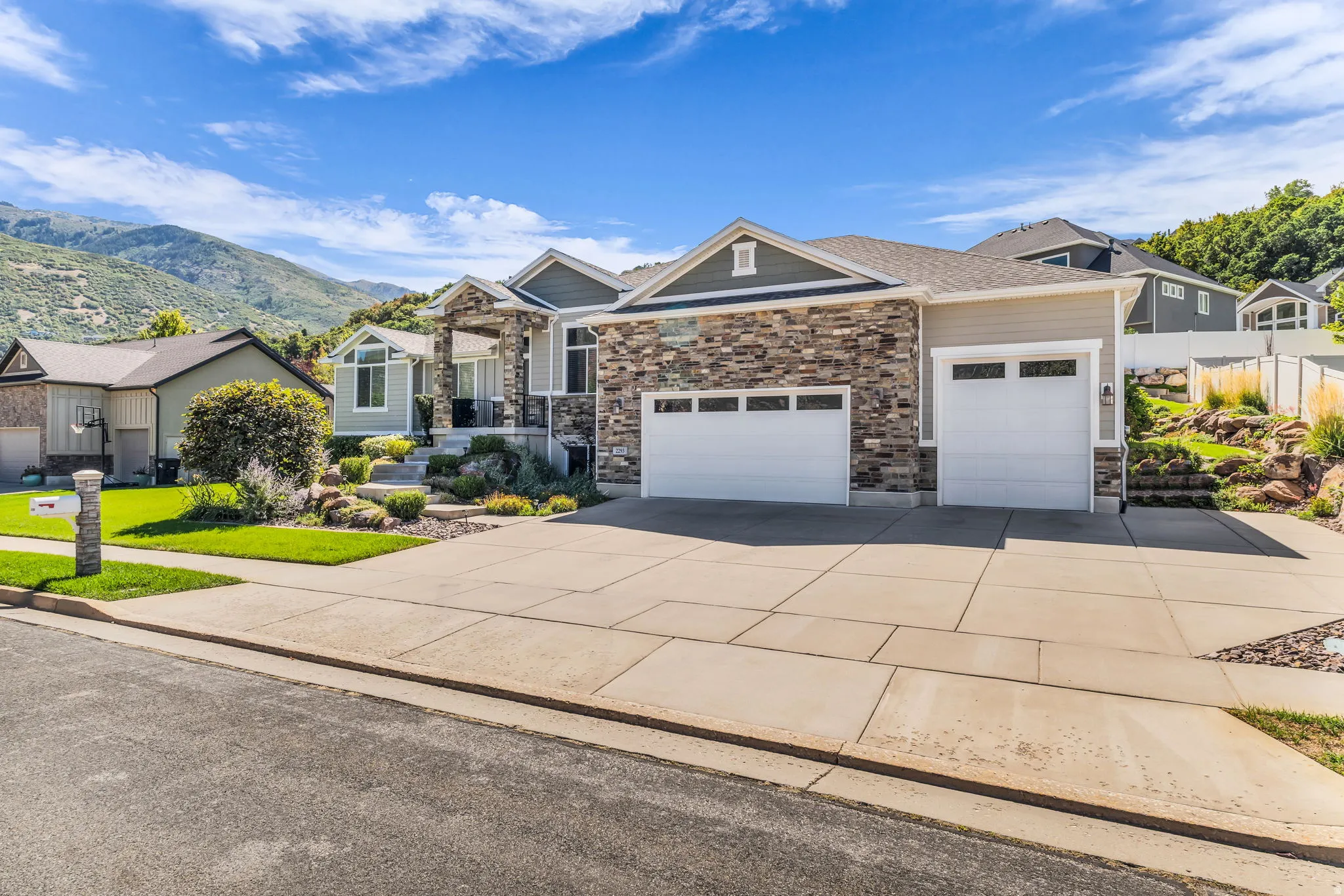 Exterior featuring stone and siding finishes, a two-car garage, and established landscaping