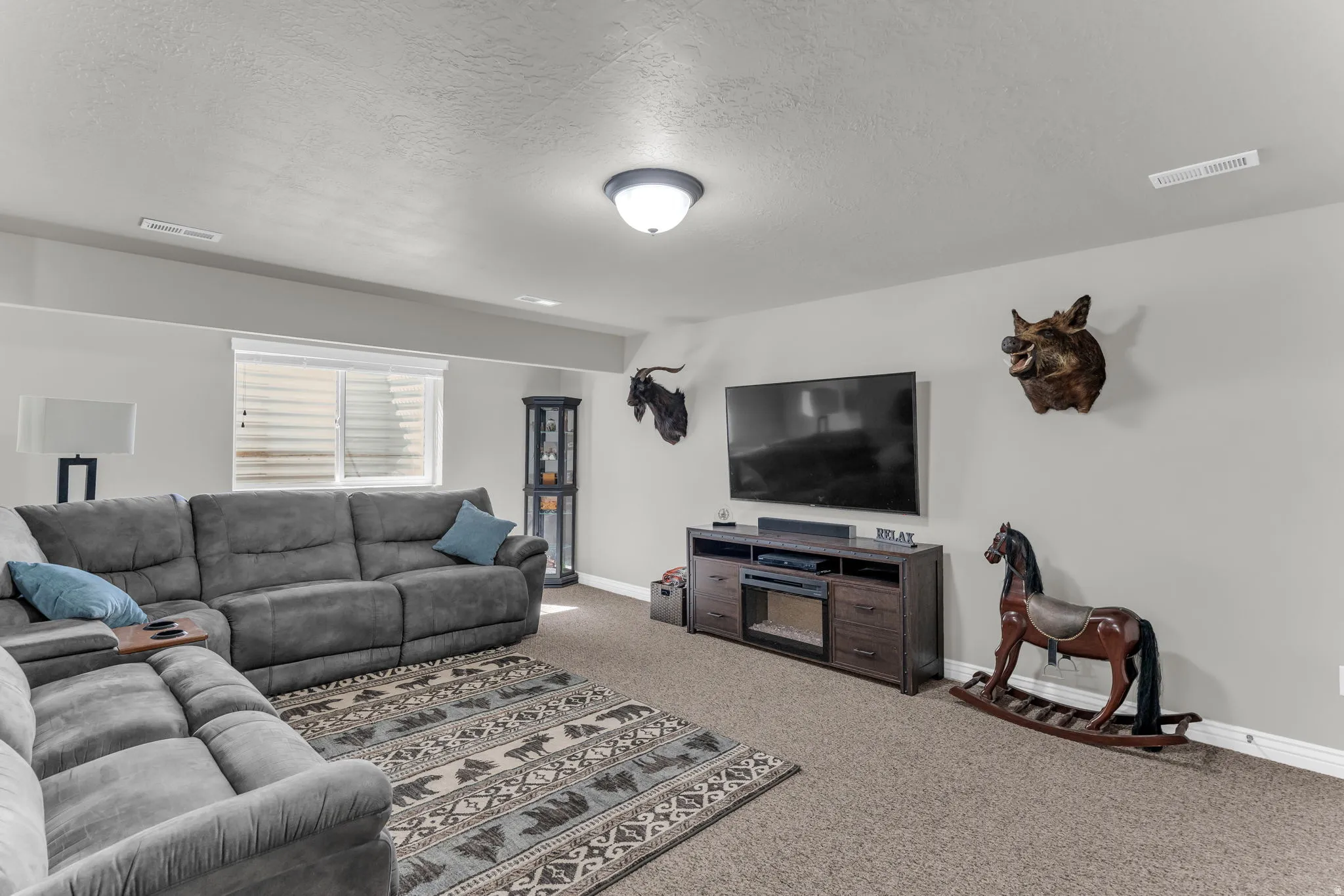 Carpeted living area with a built-in media console and an integrated electric fireplace