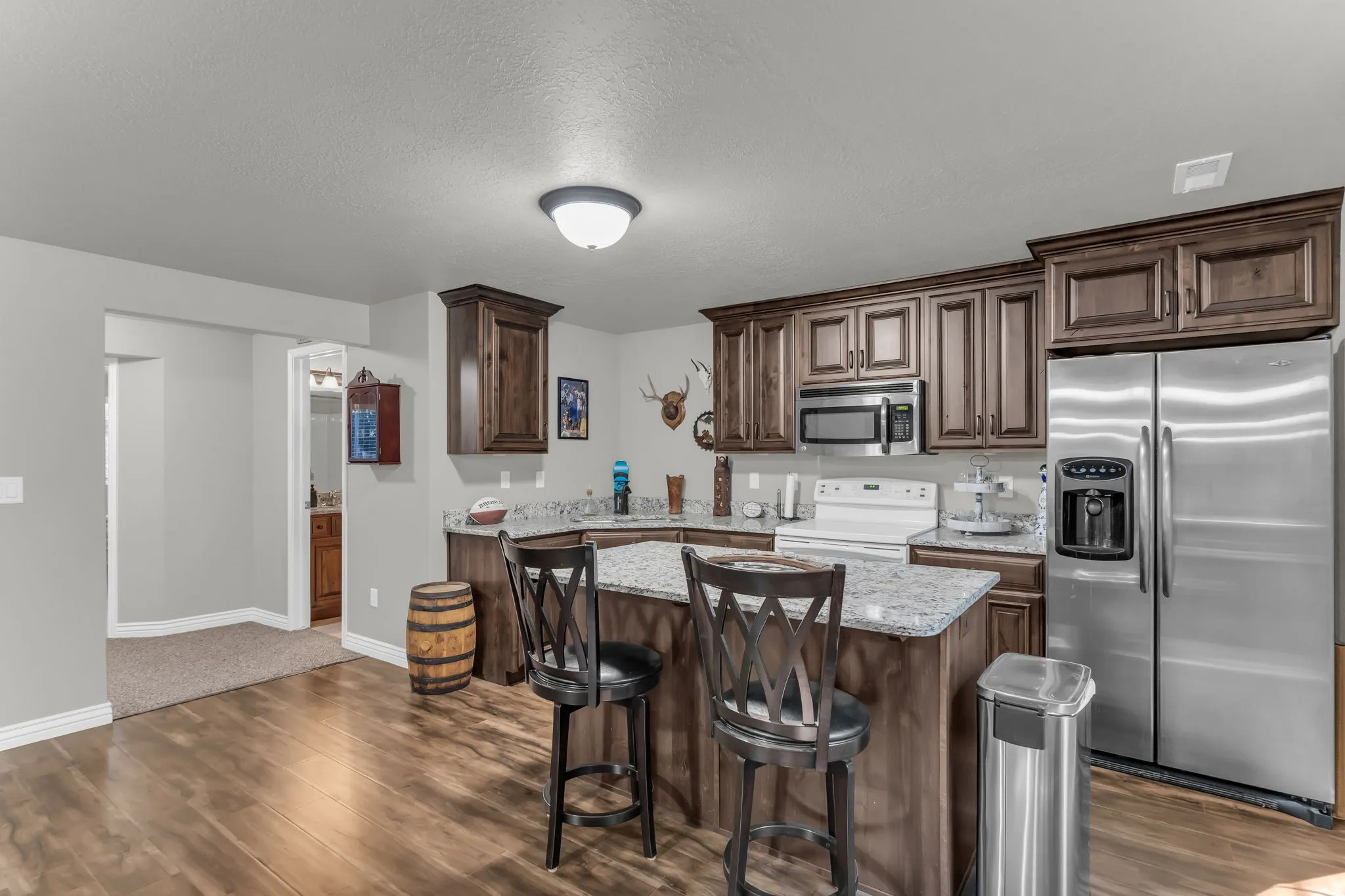 Kitchen featuring wood-finish flooring, dark wood cabinetry, stainless steel appliances, and an island with a light-toned countertop