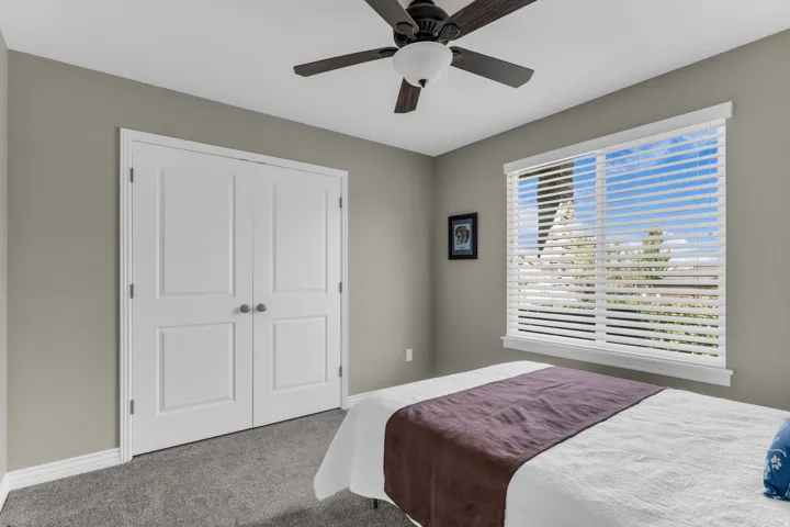 Recessed window with horizontal blinds, built-in ceiling fan with integrated lighting, paneled double doors, and soft gray carpeting