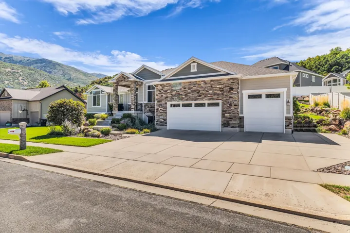 Exterior featuring stone and siding finishes, a two-car garage, and established landscaping