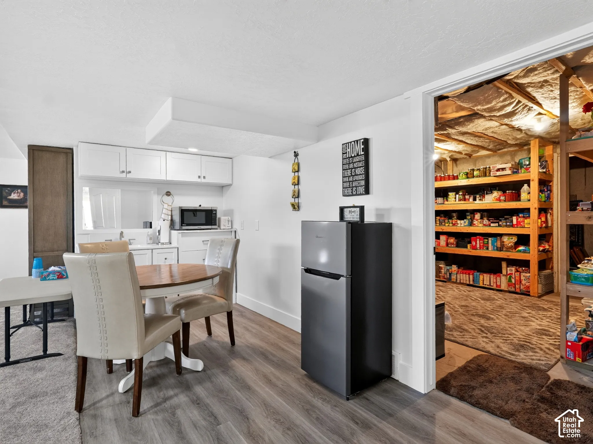 Kitchenette featuring white cabinetry, a built-in microwave, and wood-finish flooring