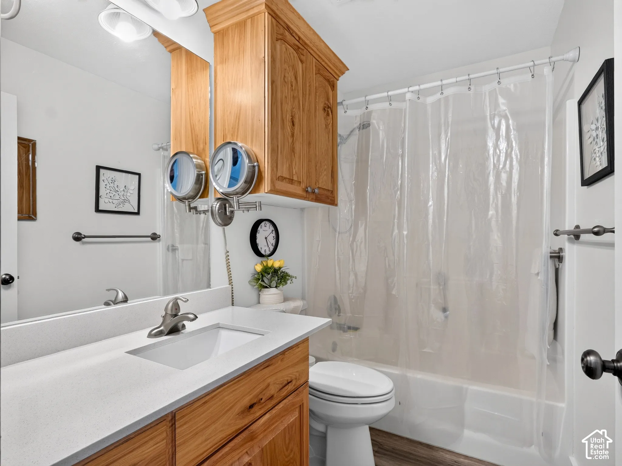 Bathroom featuring a single vanity with a white countertop and integrated sink, wood-finish cabinetry, built-in overhead cabinet, and a shower-over-tub combination