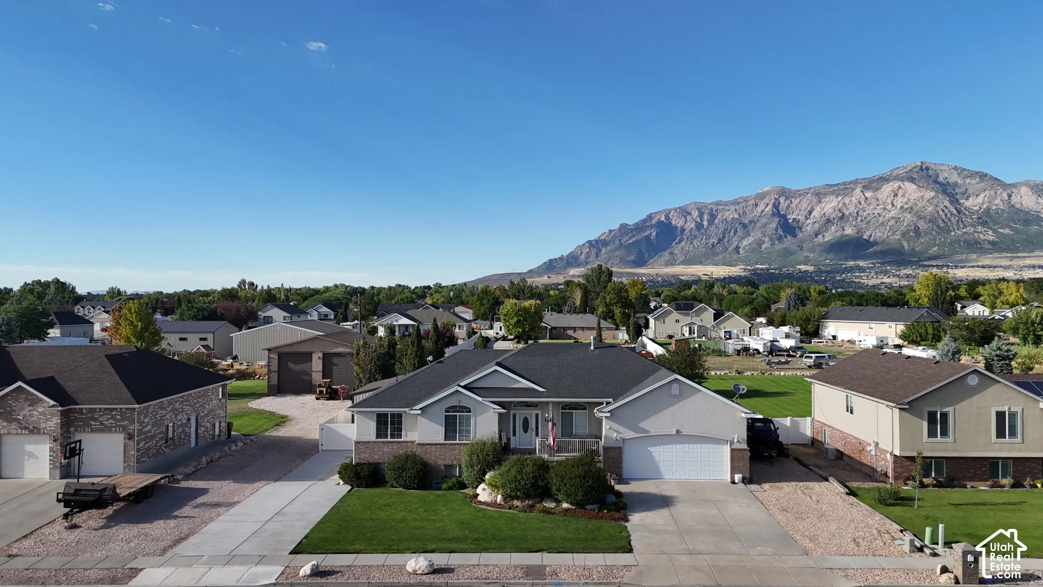 Single-story residence featuring a brick and stucco exterior, two attached garages, and a landscaped front yard with a concrete driveway