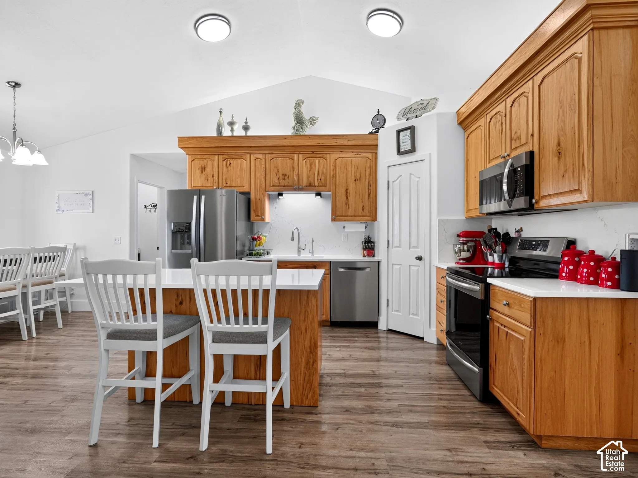 Kitchen featuring wood-finish cabinetry, stainless steel appliances, white countertops, and wood-finish flooring