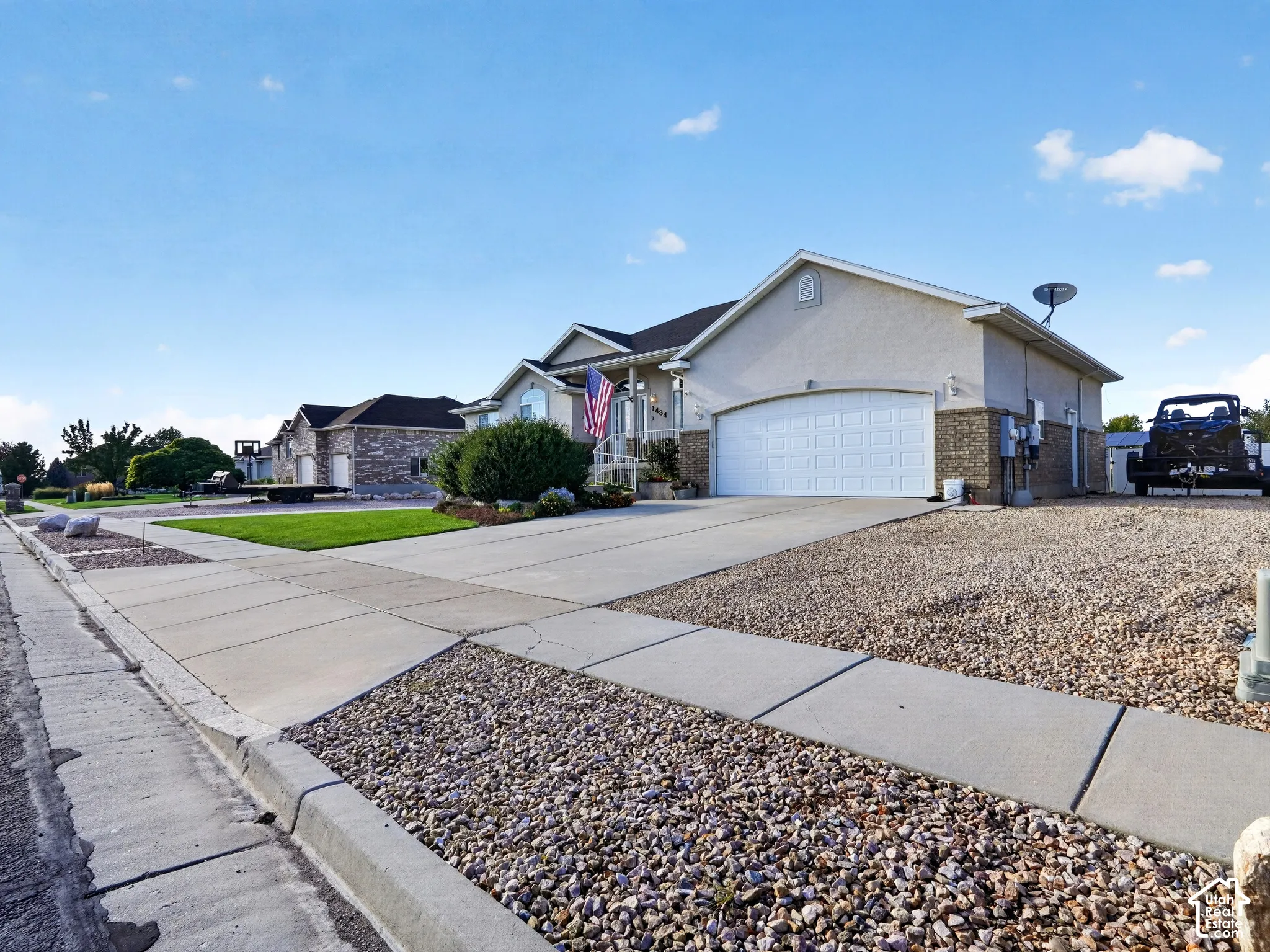 Stucco exterior with brick-finish accents, attached two-car garage, concrete driveway, and gravel landscaping